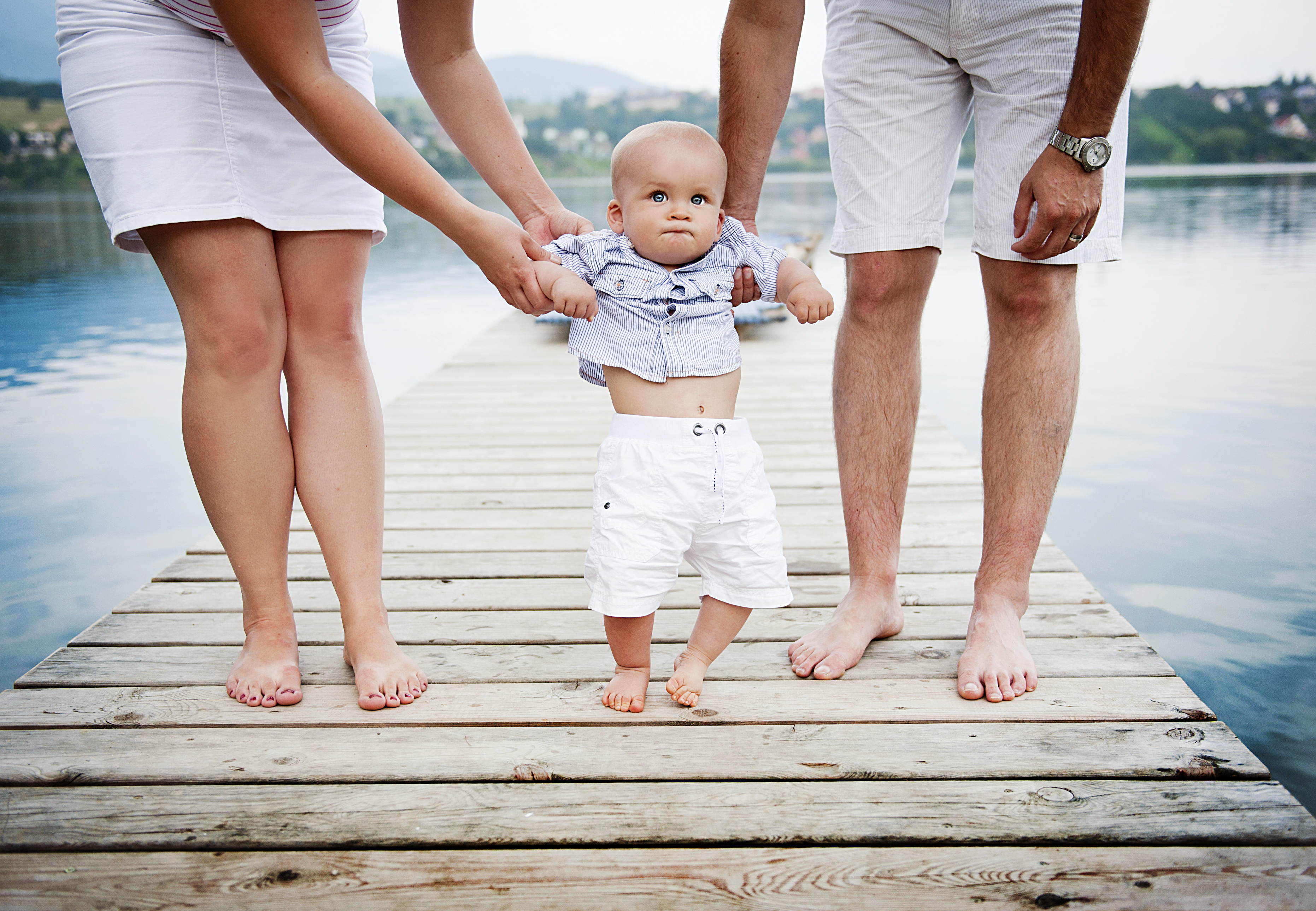 Start family. Первые шаги ребенка. Родители учат ребенка ходить. Родители с ребенком за руку. Ребенка ведут за руку.